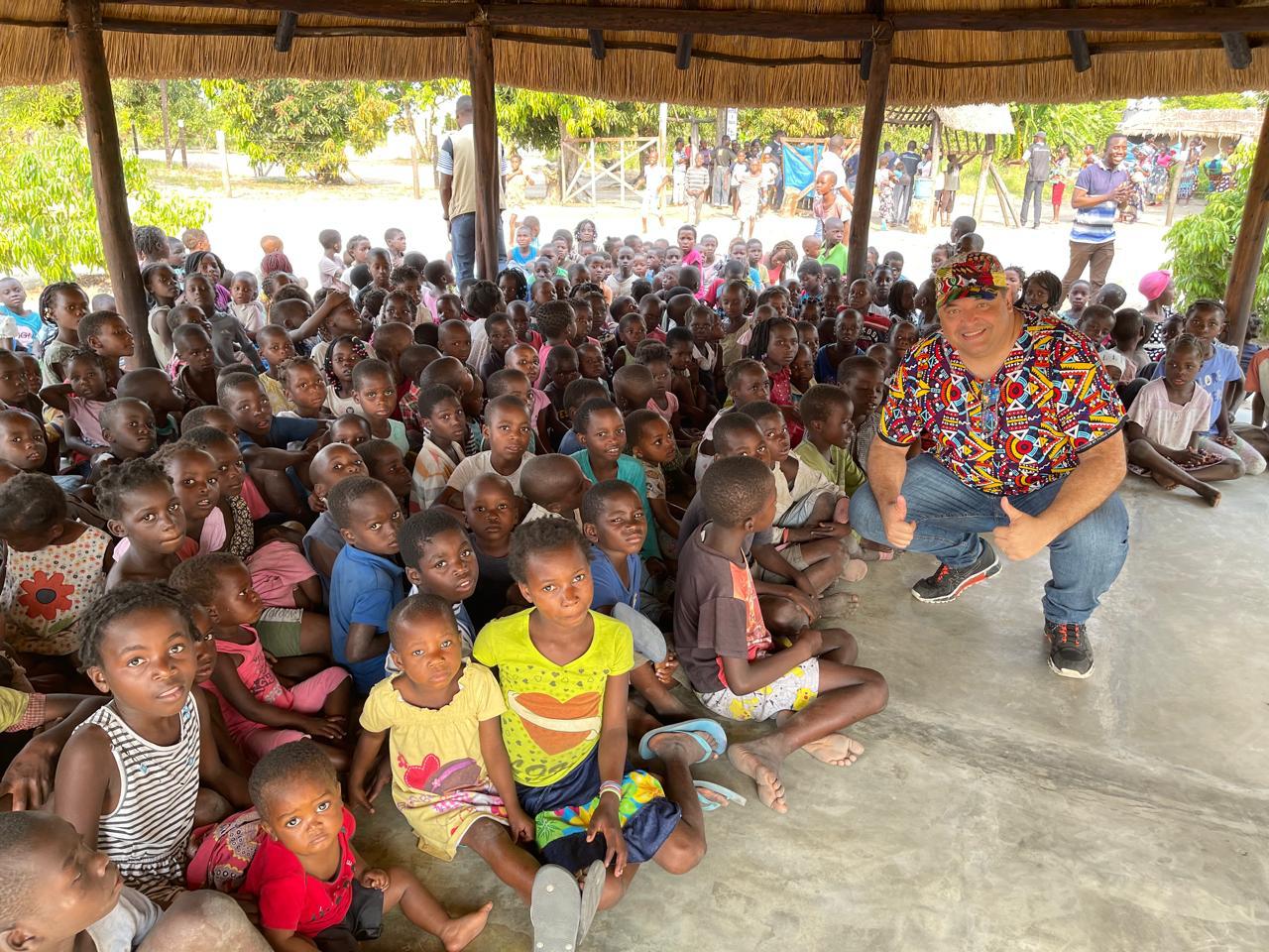 Grande grupo de crianças reunido com um voluntário do projeto durante a distribuição de alimentos