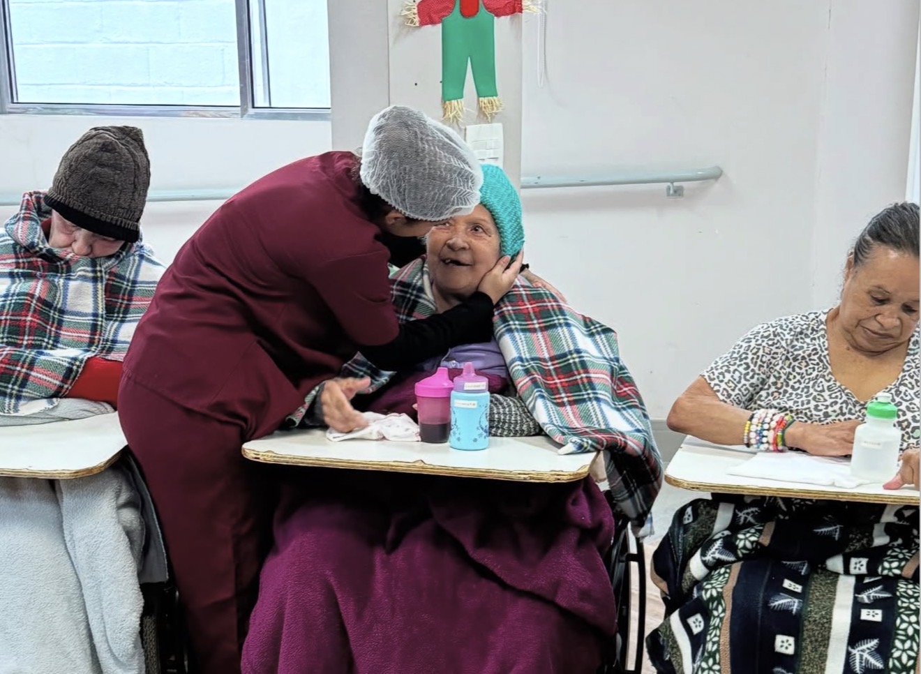 Cuidadora abraçando uma senhora idosa durante visita a um asilo no Brasil